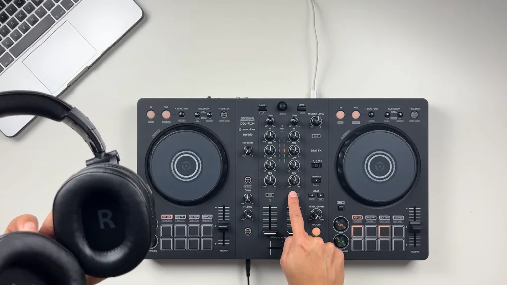 Cette image illustre un DJ manipulant un controleur, un casque et un ordinateur pour mixer.